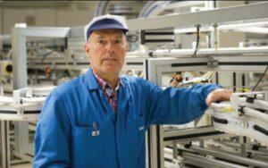Engineer in blue overalls working at an aluminium framed conveyor in a production hall