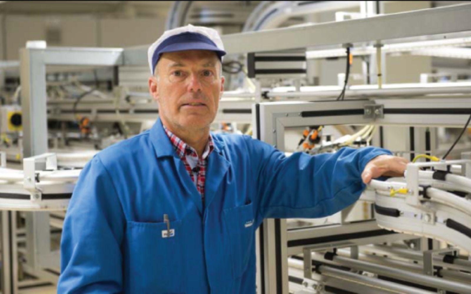 Engineer in blue overalls working at an aluminium framed conveyor in a production hall