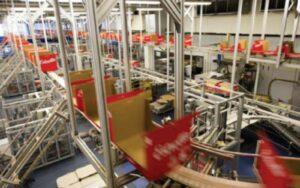 Red plastic crates moving along an elevated crate handling conveyor line inside a factory