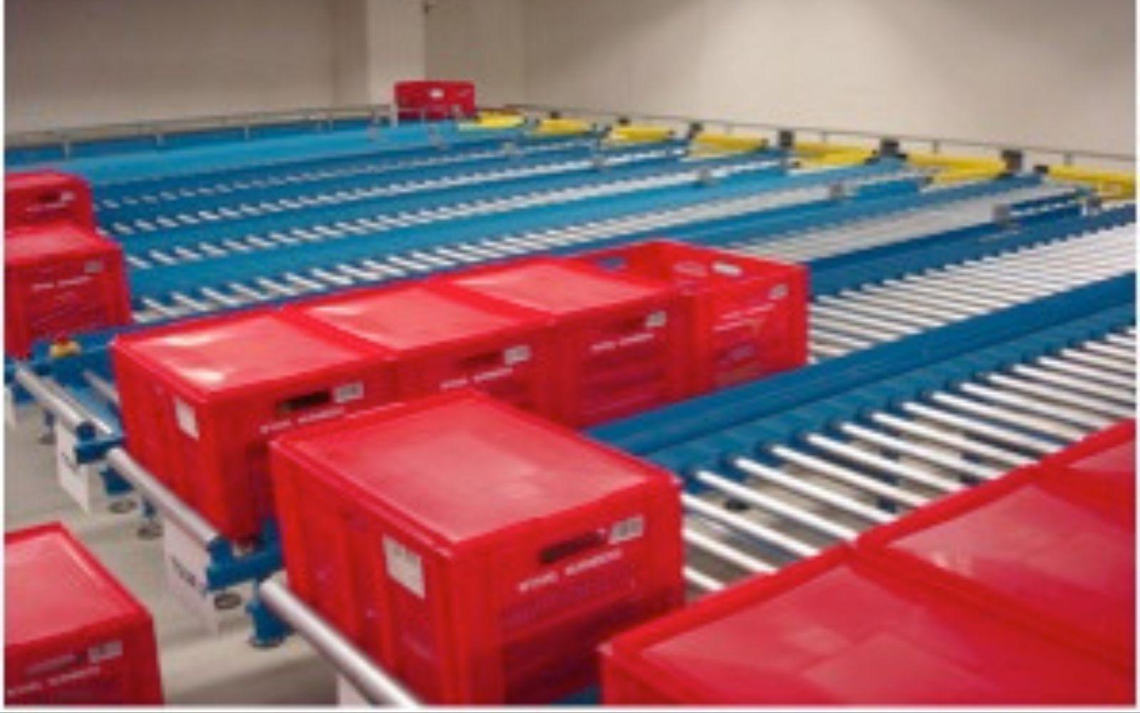 Red plastic totes travelling on gravity roller conveyor lanes in a distribution centre