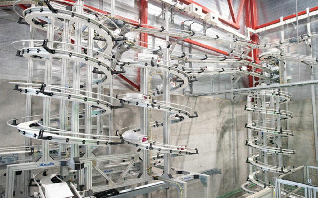 Multi tier overhead spiral conveyor system carrying product on tracks through a plant
